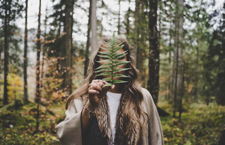 Ragazza che tiene in mano una foglia in una foresta