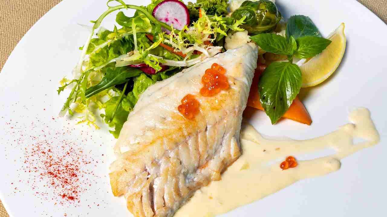 Piatto contenente del pesce cotto e delle verdure in insalata