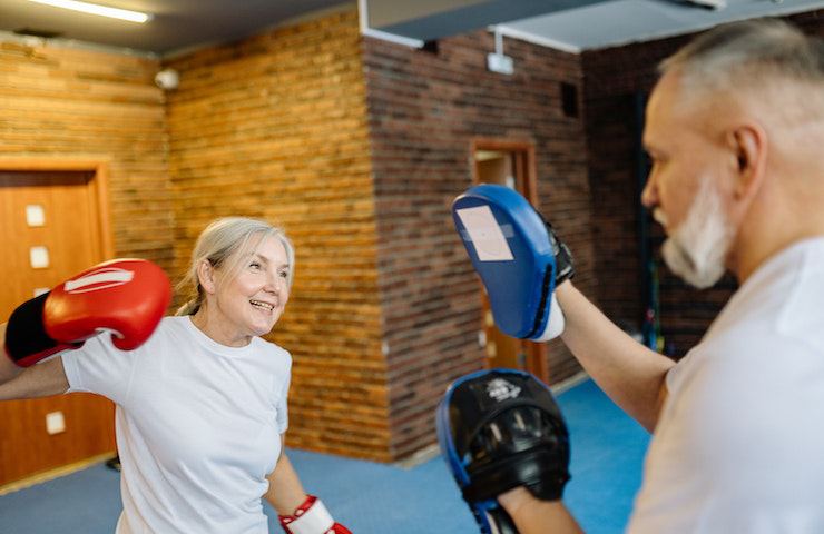 Donna che fa un esercizio con il suo allenatore durante un allenamento di boxe