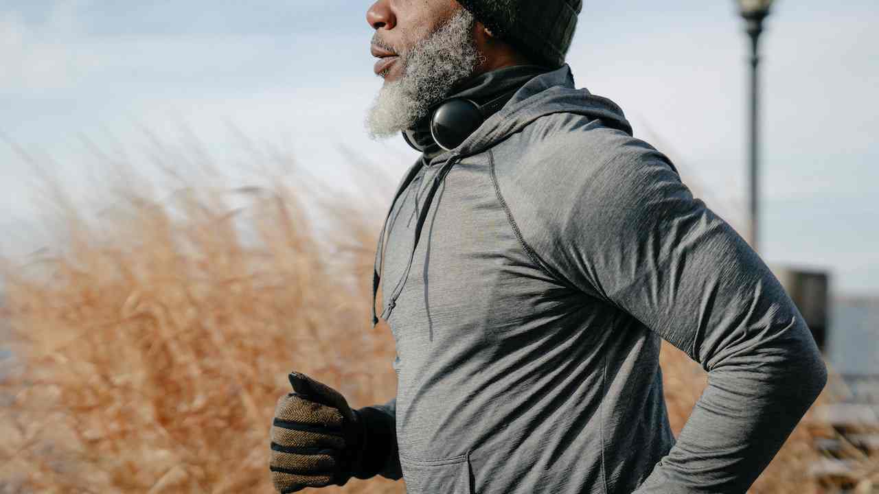 Primo piano di un uomo in tuta e cappellino mentre corre