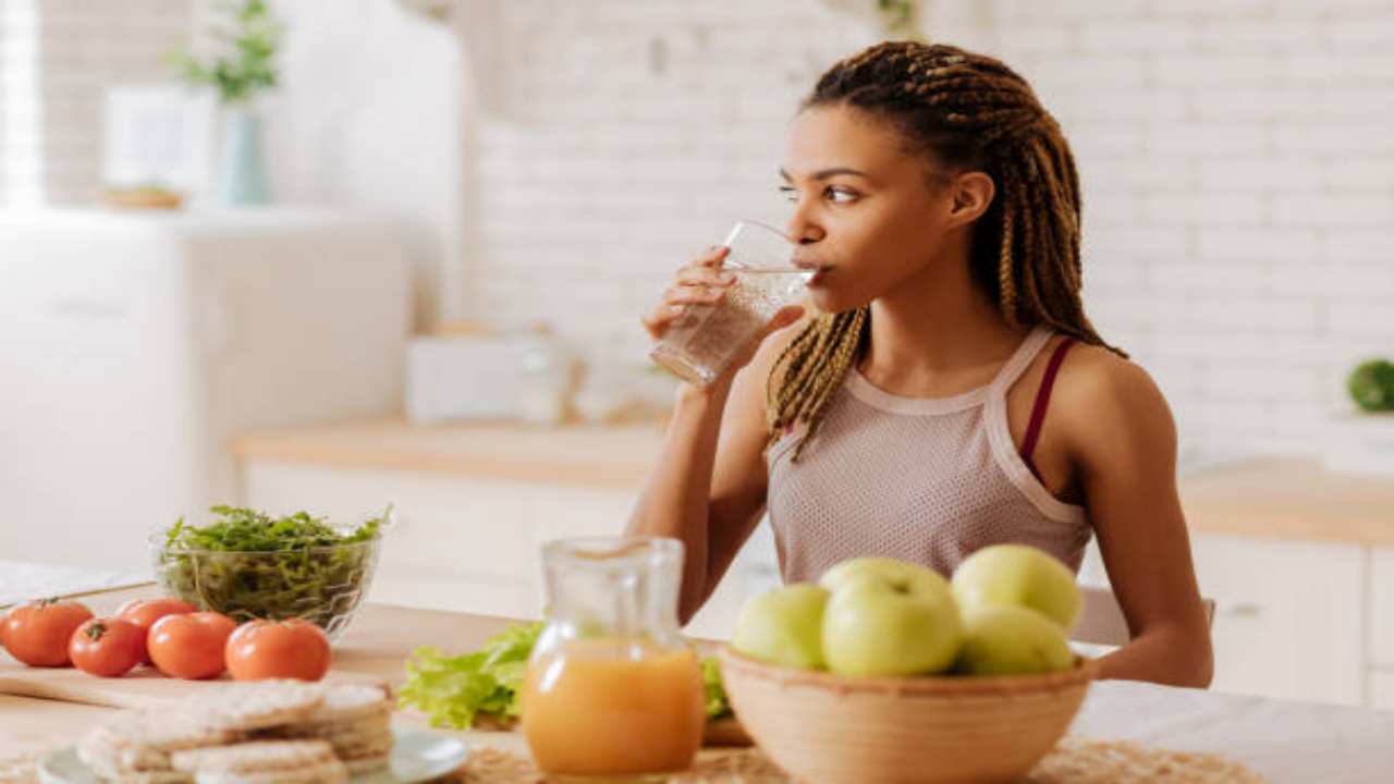 Ragazza che beve acqua mentre mangia