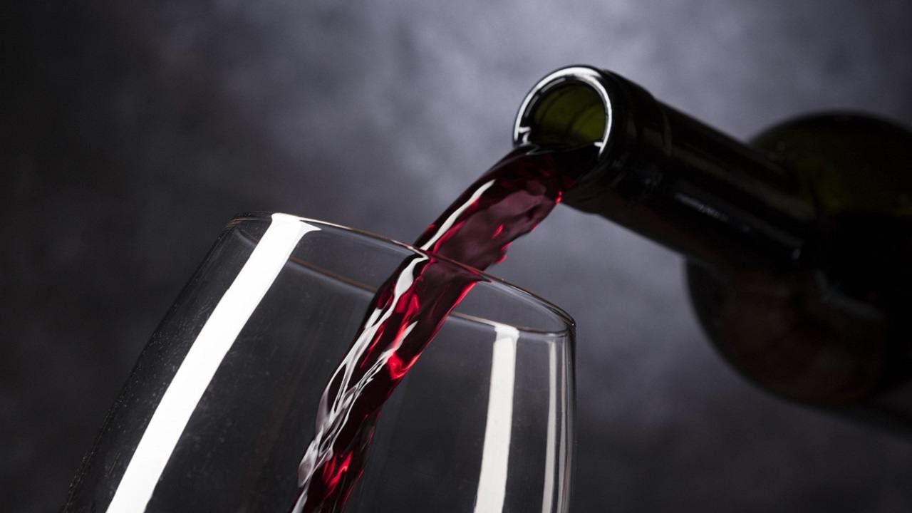 Vino rosso versato da una bottiglia in un bicchiere