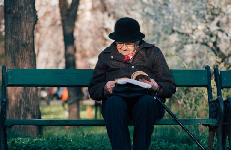 Anziana che legge al parco