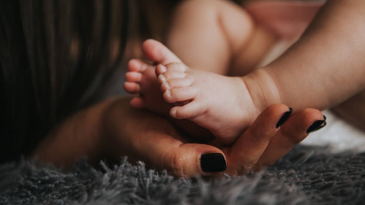 Una donna accarezza i piedi del suo bambino