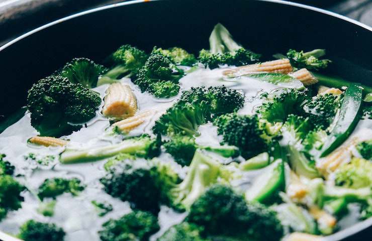 Broccoli immersi in un brodo in pentola, con altre verdure