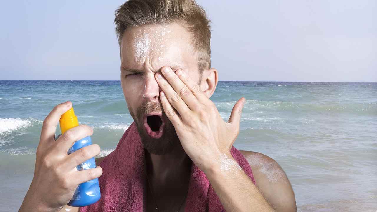 Ragazzo si mette la crema solare al mare