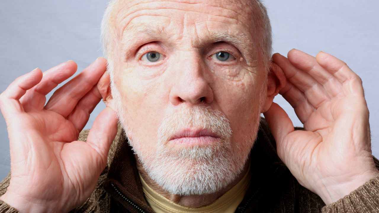 Uomo colpito da ipoacusia porge in avanti le orecchie per sentire meglio