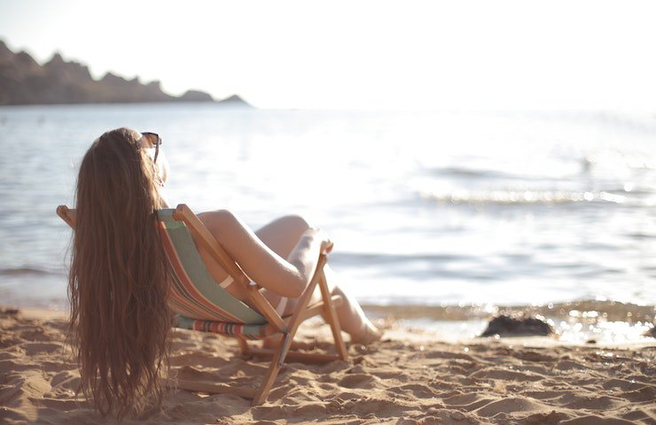 Ragazza prende il sole in spiaggia. Modo per non avere carenza di vitamina d