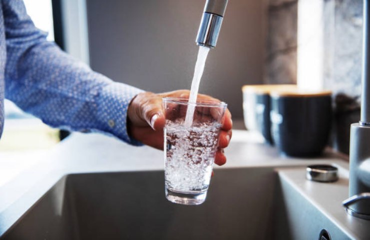 Ragazzo riempie un bicchiere d'acqua