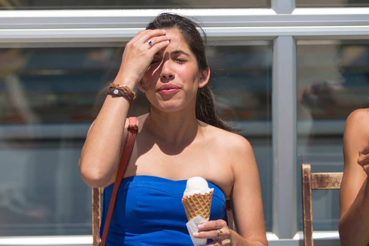 Ragazza si tiene la testa mangiando il gelato per un'improvvisa emicrania