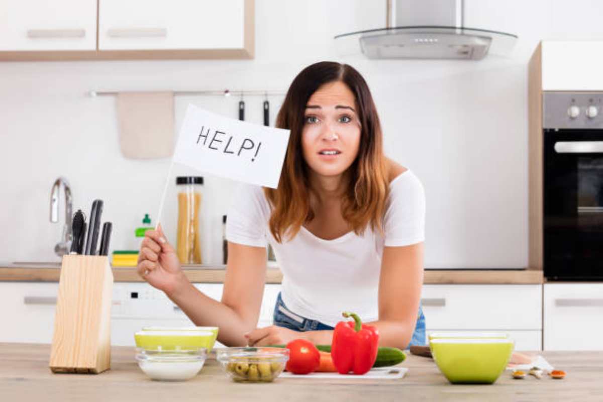 Ragazza con una bandiera bianca con scitto "aiuto" in cucina