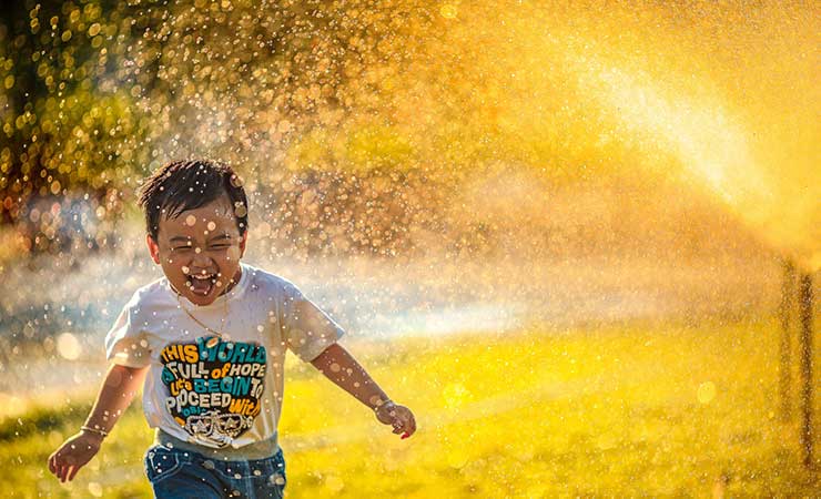 un bambino si rinfresca giocando con l'acqua