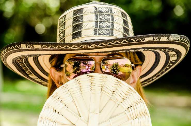 Donna con occhiali, cappello e ventaglio si protegge dal caldo e dal sole