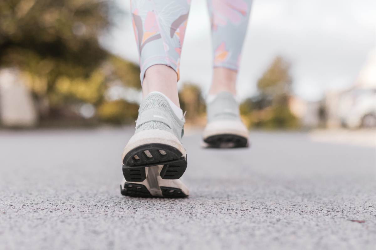 Vista ravvicinata di un paio di piedi che camminano in scarpe da ginnastica di una persona con dei legginns