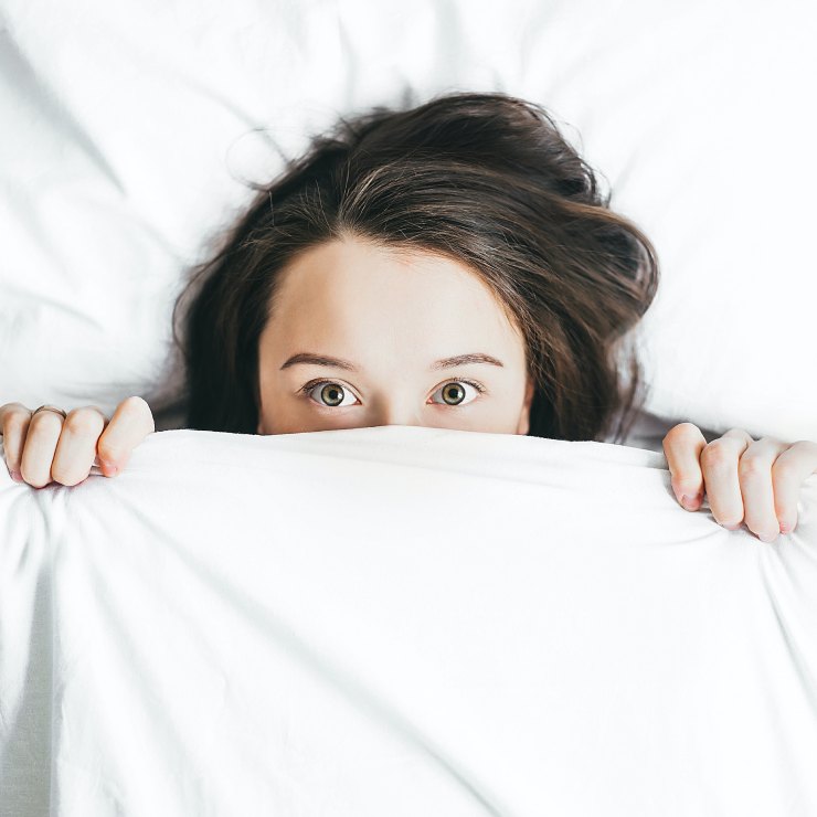 Ragazza spaventata si nasconde sotto le coperte