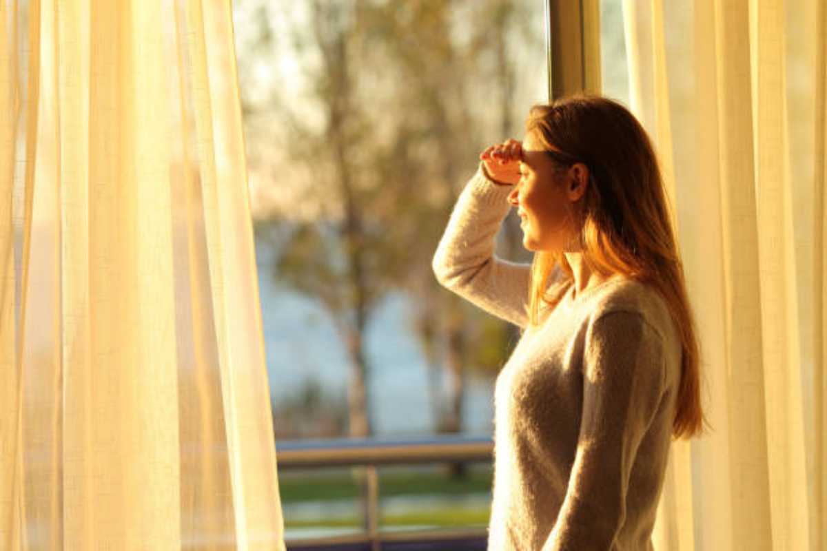 Ragazza guarda dalla finestra di casa la luce del Sole