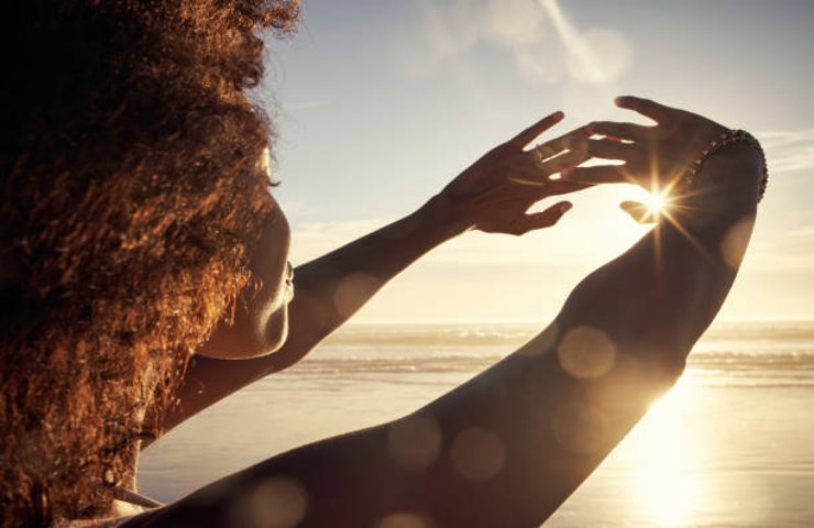 Ragazza guarda direttamente la luce del Sole al mare