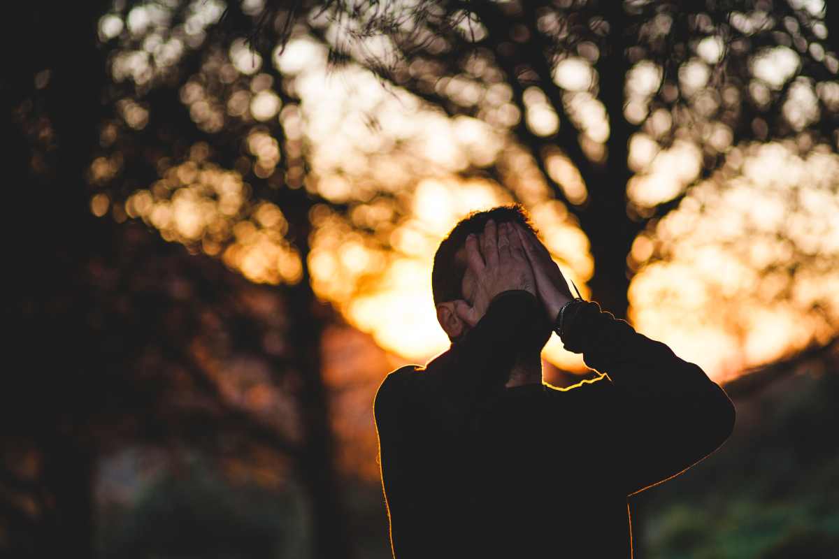 Uomo colpito da labirintite da stress si mette le mani al volto