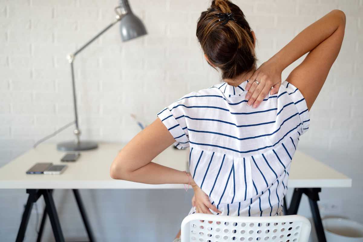 Una donna si massaggia la schiena dolorante