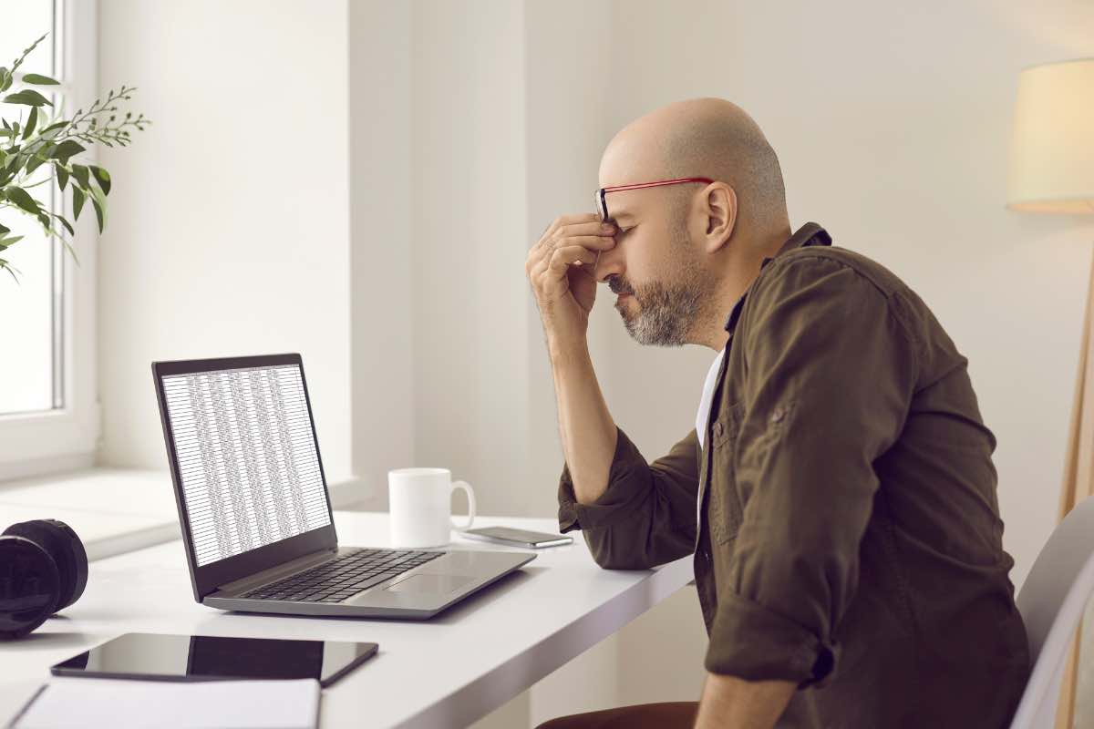 Un uomo visibilmente affaticato davanti al pc