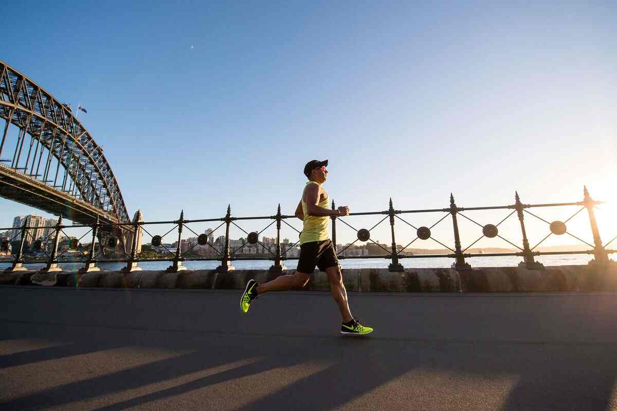 uomo corre al sole su un ponte bordo fiume