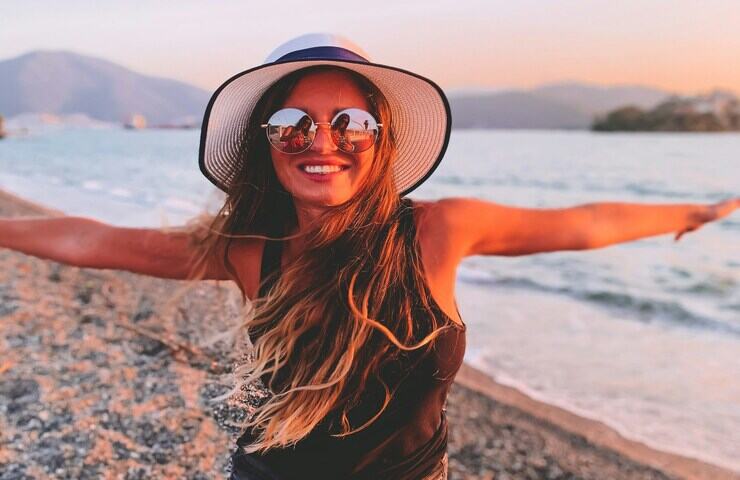 ragazza con cappello e occhiali da sole in spiaggia