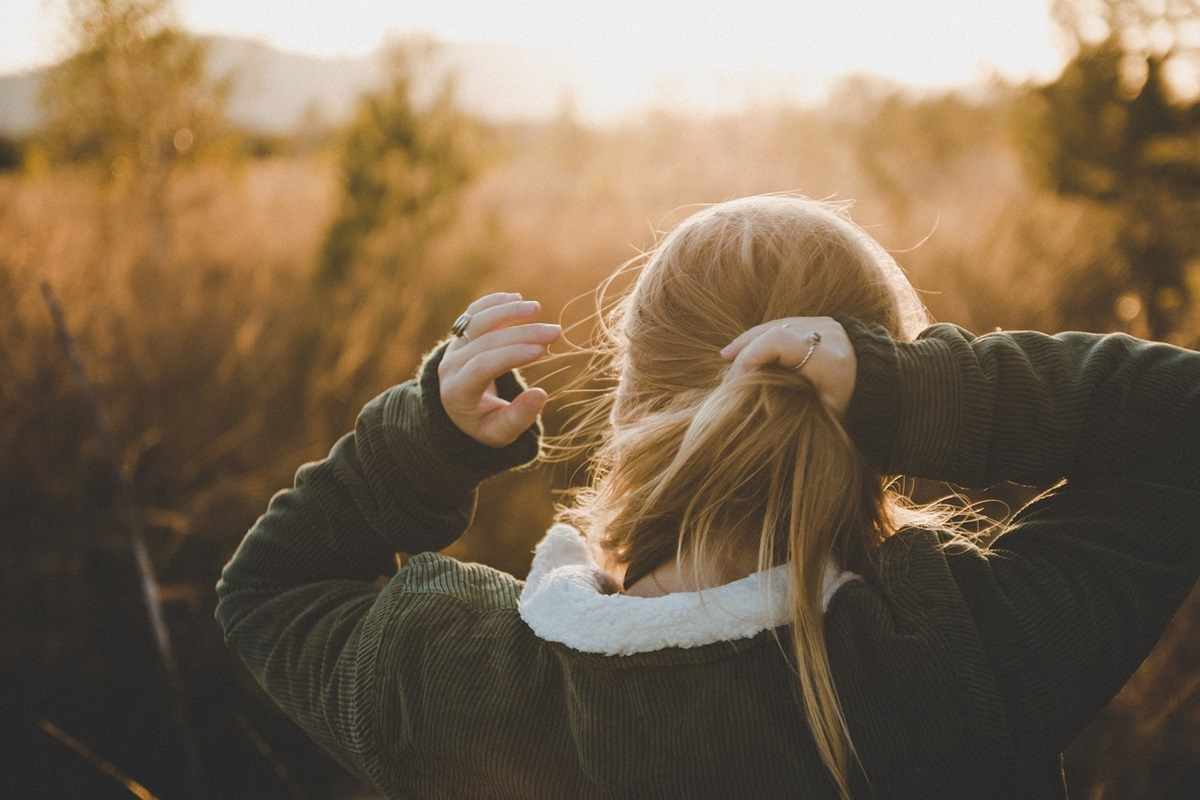 Una donna intenta a legarsi i capelli