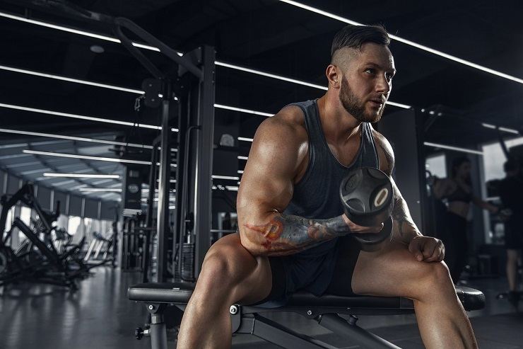 Un uomo si allena in palestra con dei pesi